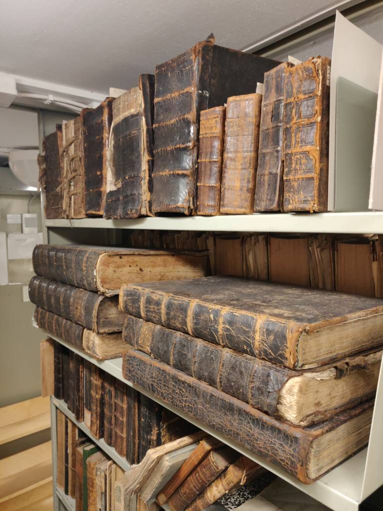Old, large Finnish books on a bookshelf.