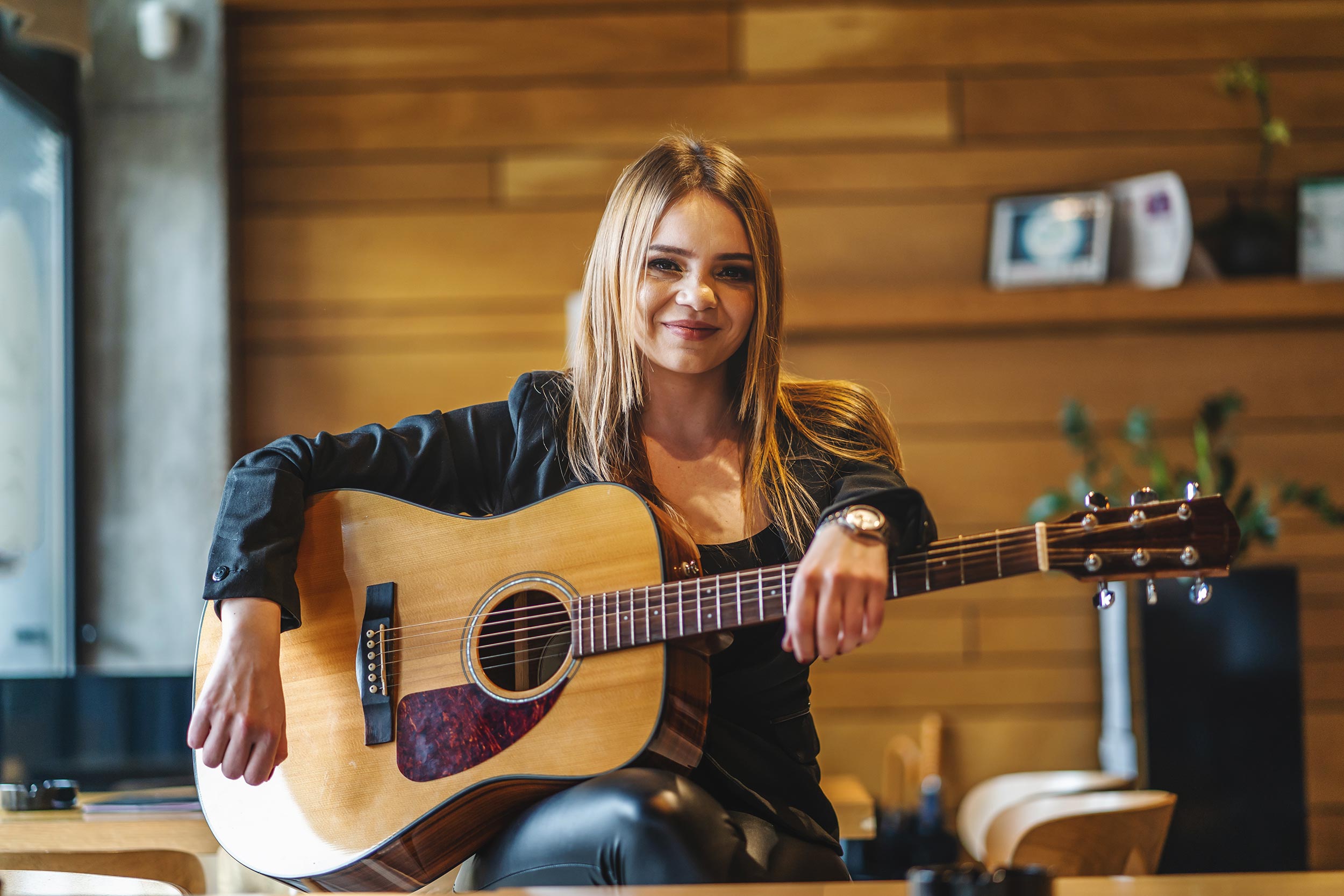A women holding on a well kept acoustic guitar